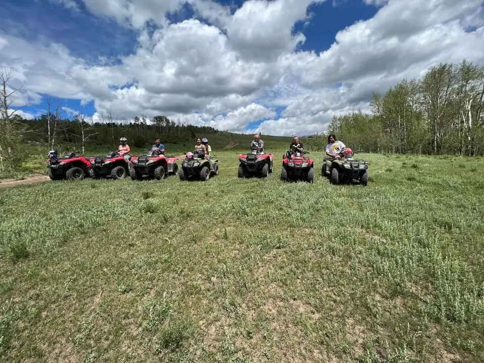 People riding ATVs on a grassy field.